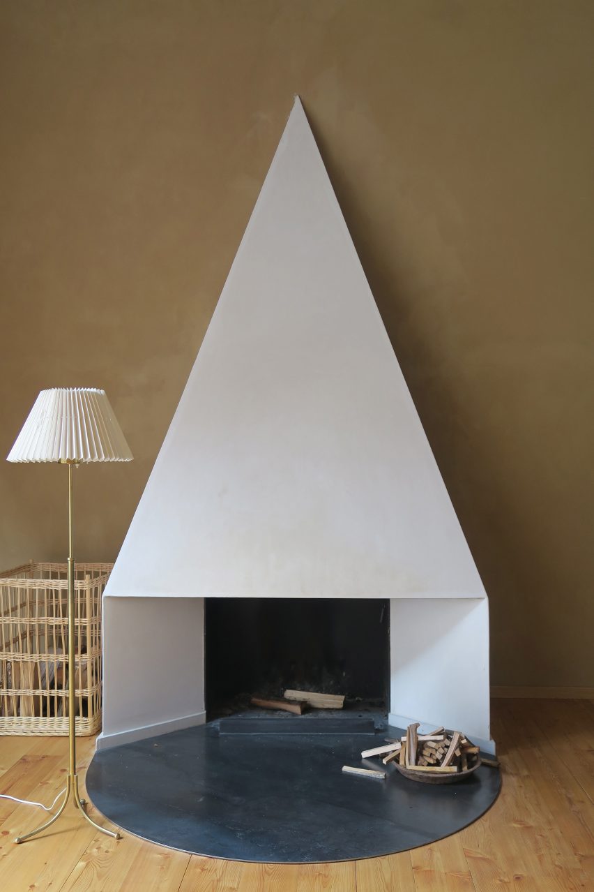 Pointy white fireplace in front of brown wall in interior by Philipp von Matt
