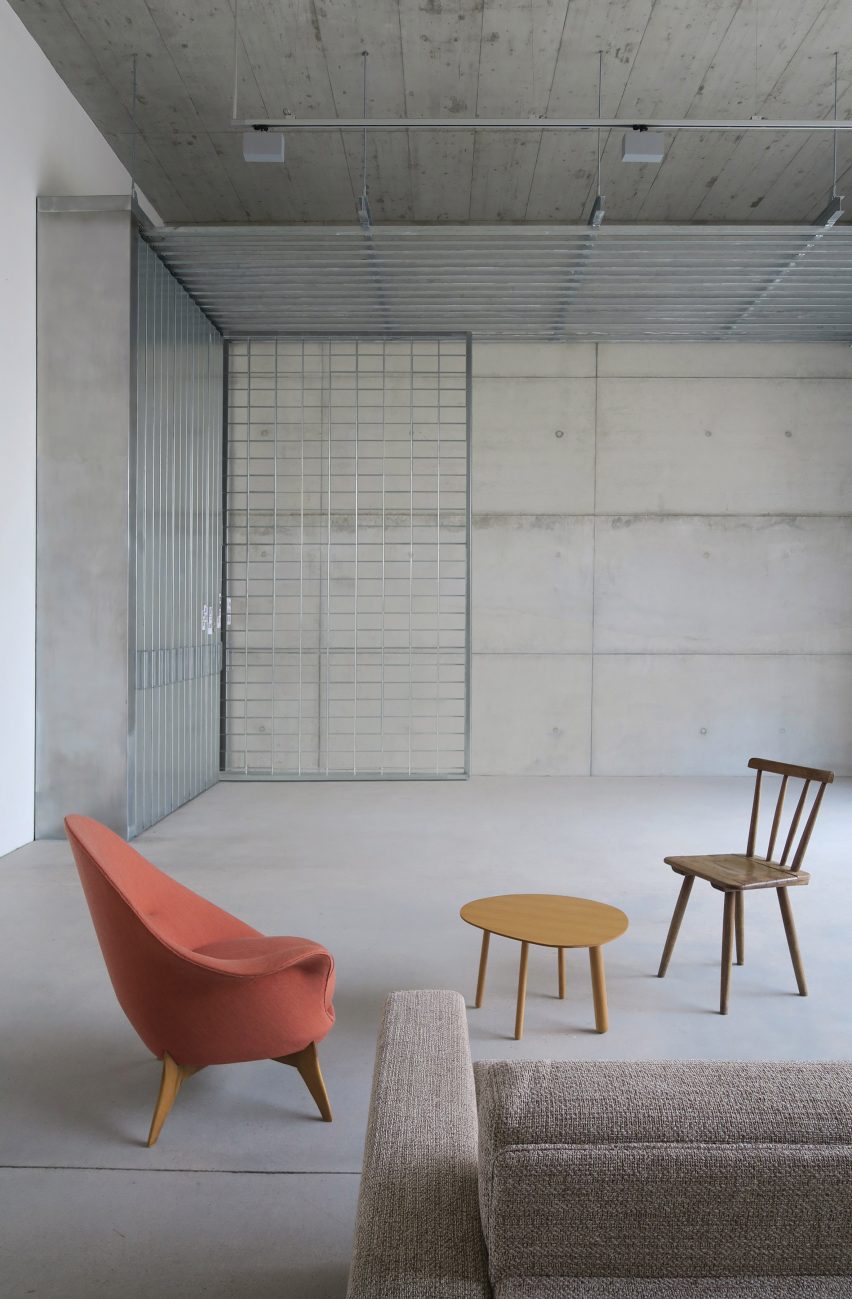 Concrete room with coral coloured armchair and wooden furnishings in Berlin home by Philipp von Matt