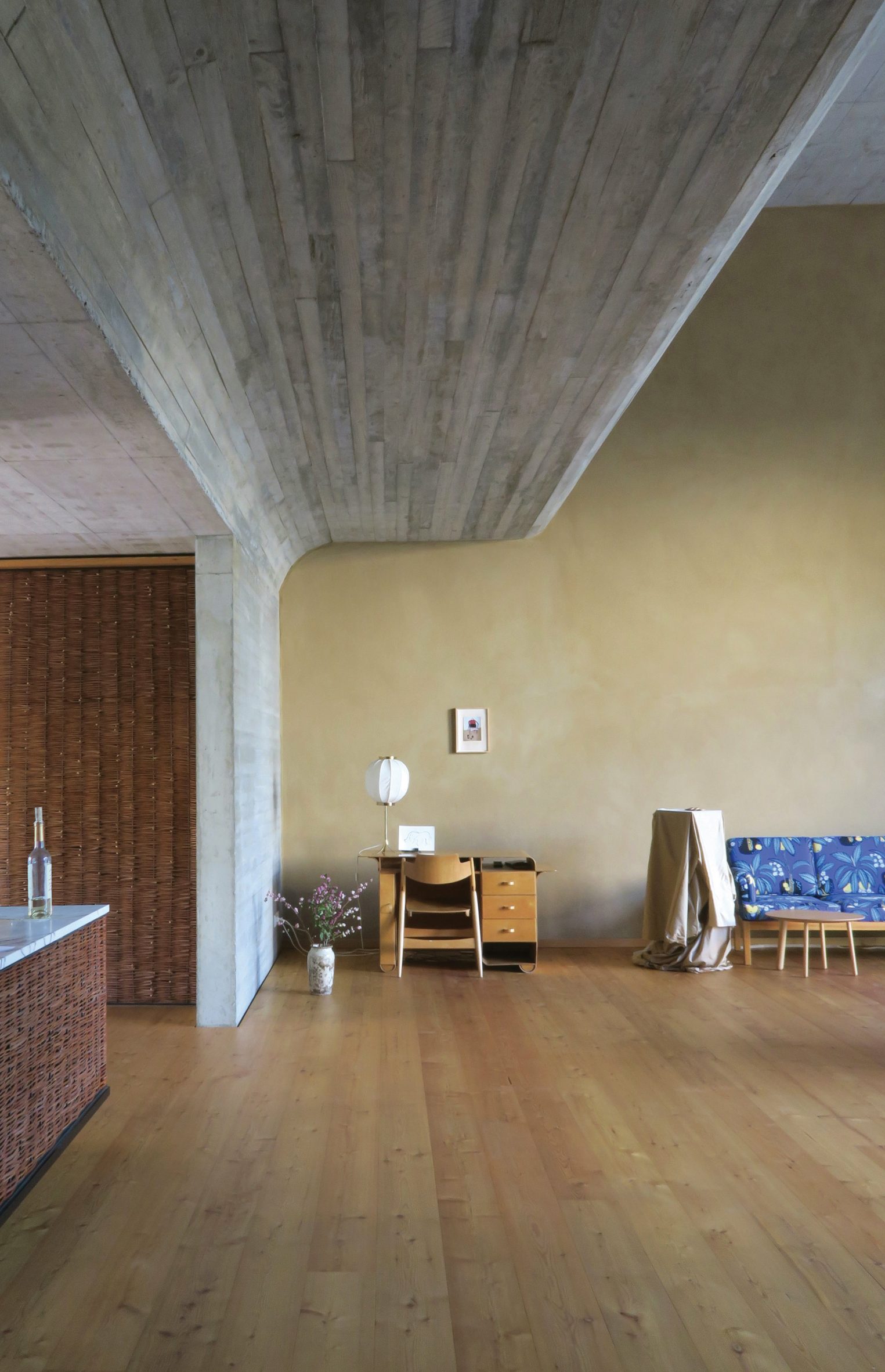Room with curved concrete ceiling and wooden floors in O12 residence