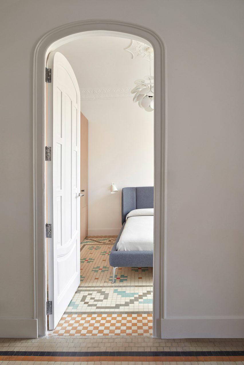 Door to bedrrom with simple blue bed and tiled mosaic floors in apartment by interior by DG Arquitecto