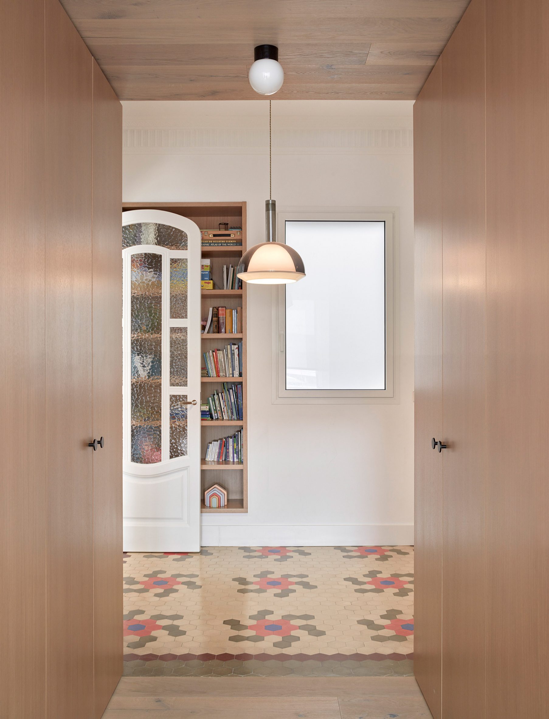 Wooden bookcase franked by wardrobes in interior by DG Arquitecto