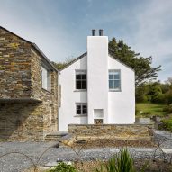 A white house with a stone-clad extension