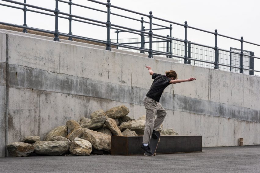 Skater on a steel box tube in front of stones in Skating Situations installation by Assemble