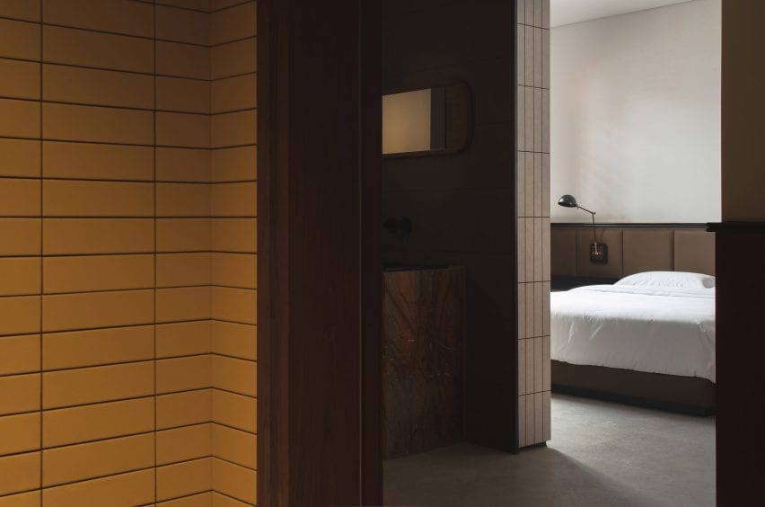 Yellow-tiled hallways and bed with white sheets in hotel interior by Archetype