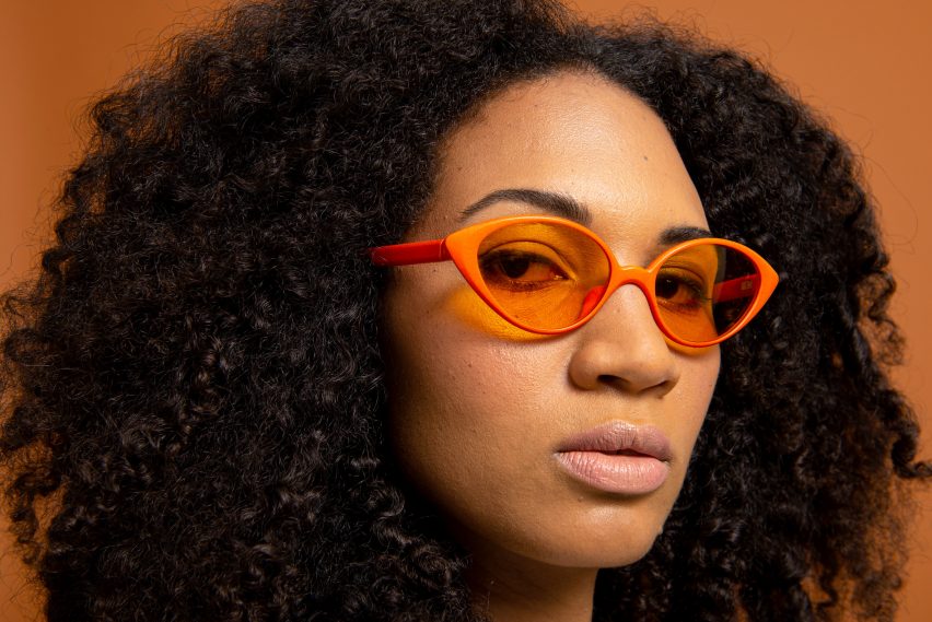 Seorang wanita mengenakan kacamata hitam Refrad berwarna oranye