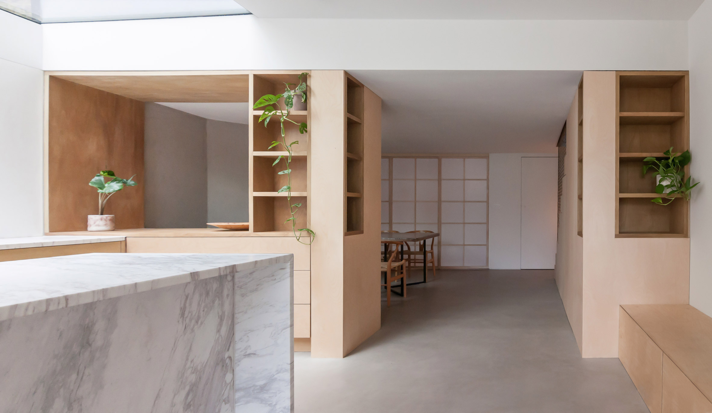 A white kitchen with a marble island and wooden cabinets