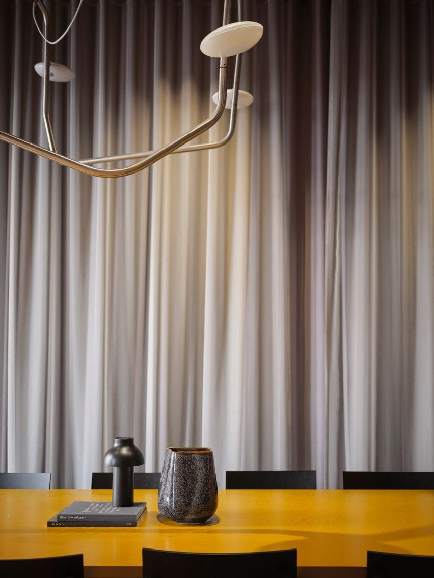 Tirai abu-abu kontras dengan meja kuning 