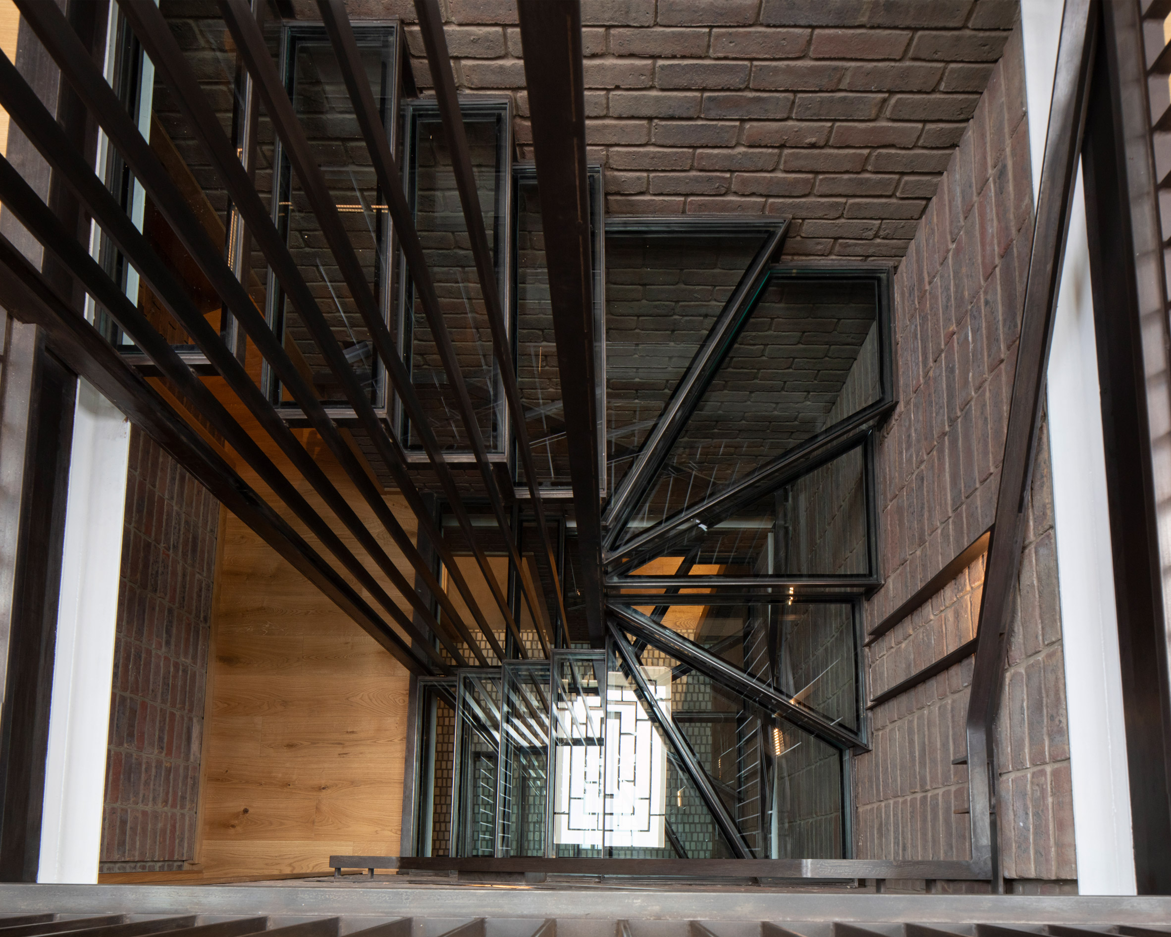 A blackened steel and glass staircase under a skylight