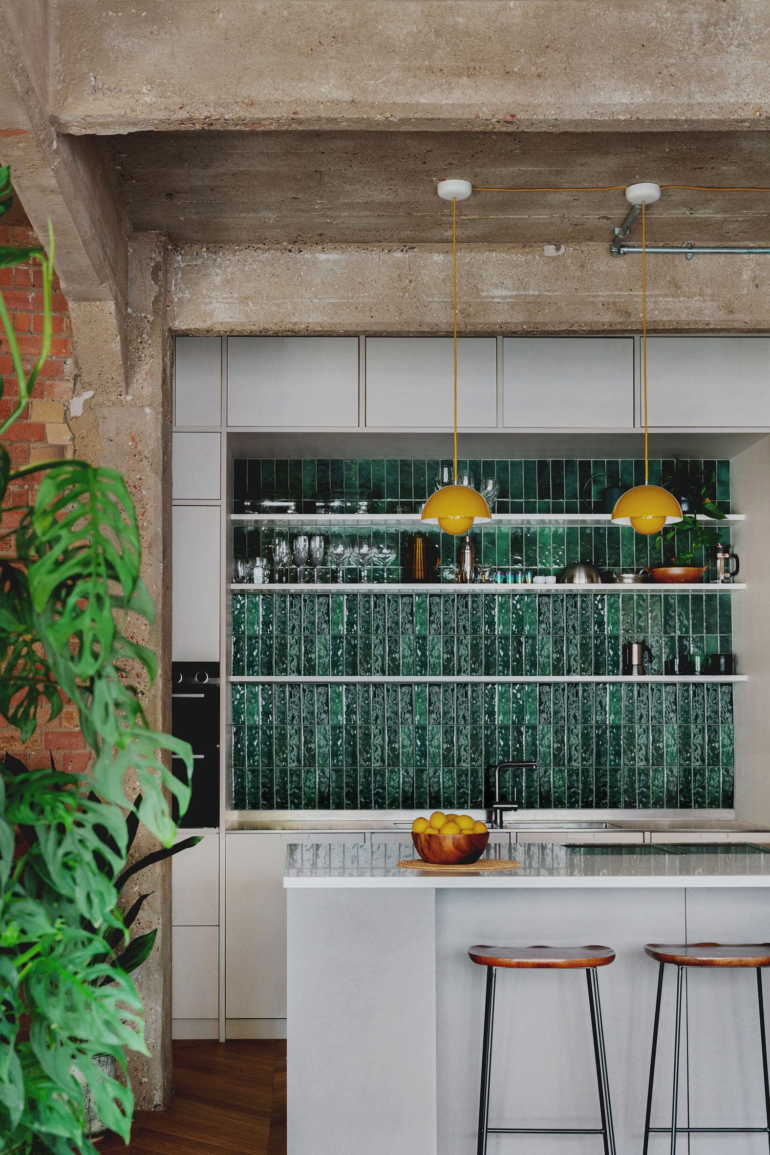 Kitchen with green tiles and birch plywood cabinets in St John Street warehouse apartment by Emil Eve Architects