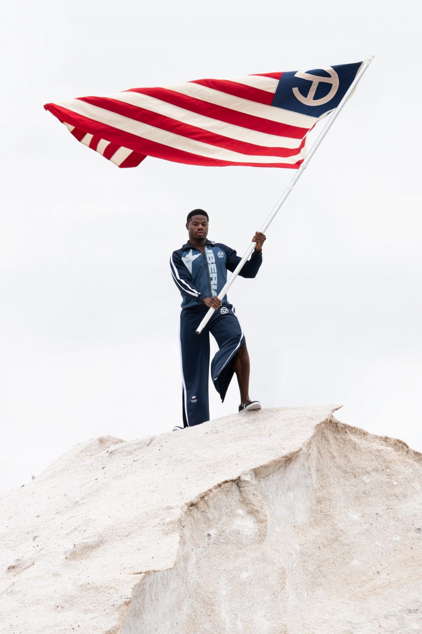 A man waves a flag while wearing the Telfar Olympic uniform