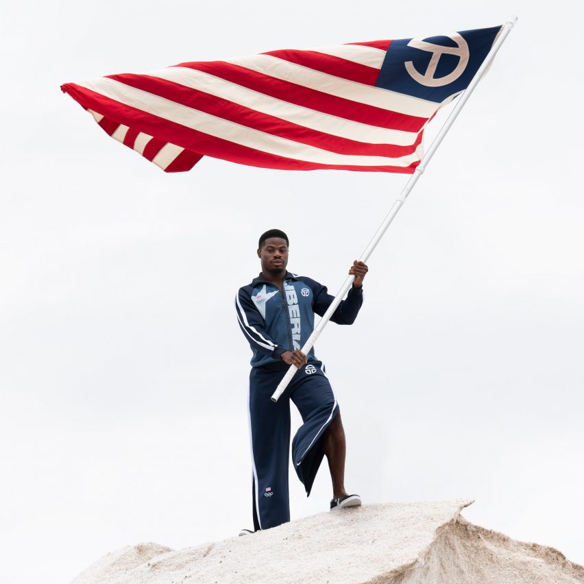 a man waving the liberian flag wearing telfar olympic uniform