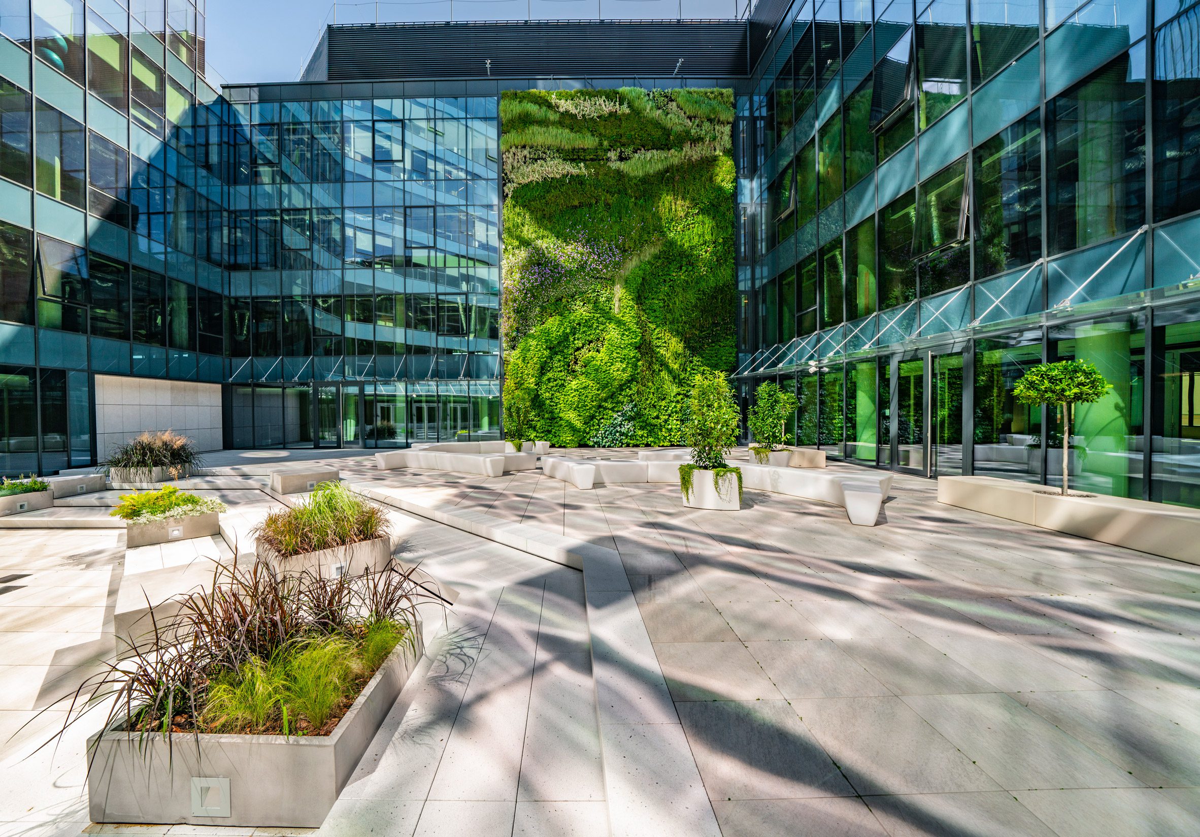 A photograph of glass building with green wall