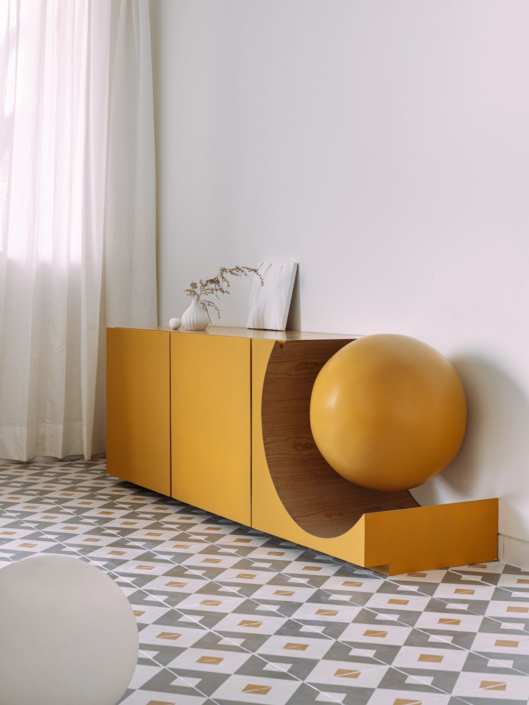 Mustard yellow cupboard with sphere cutout in interior by The Act of Quad