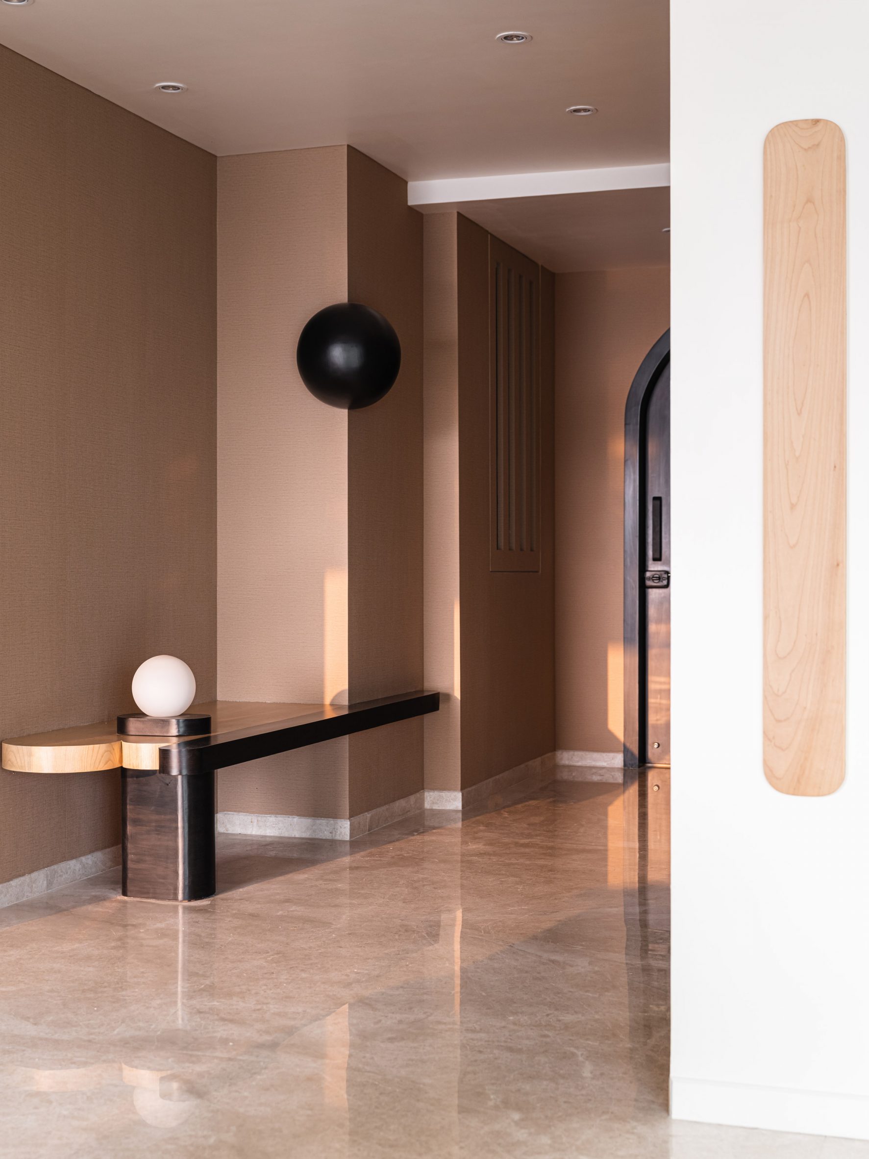 Entrance hall with brown painted walls and wooden console with white sphere in Mumbai apartment