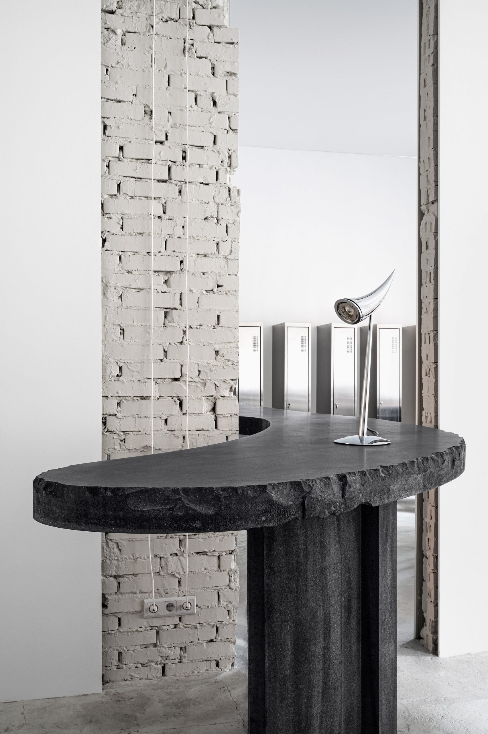 Curved concrete table with chrome light in 6:19 Studio