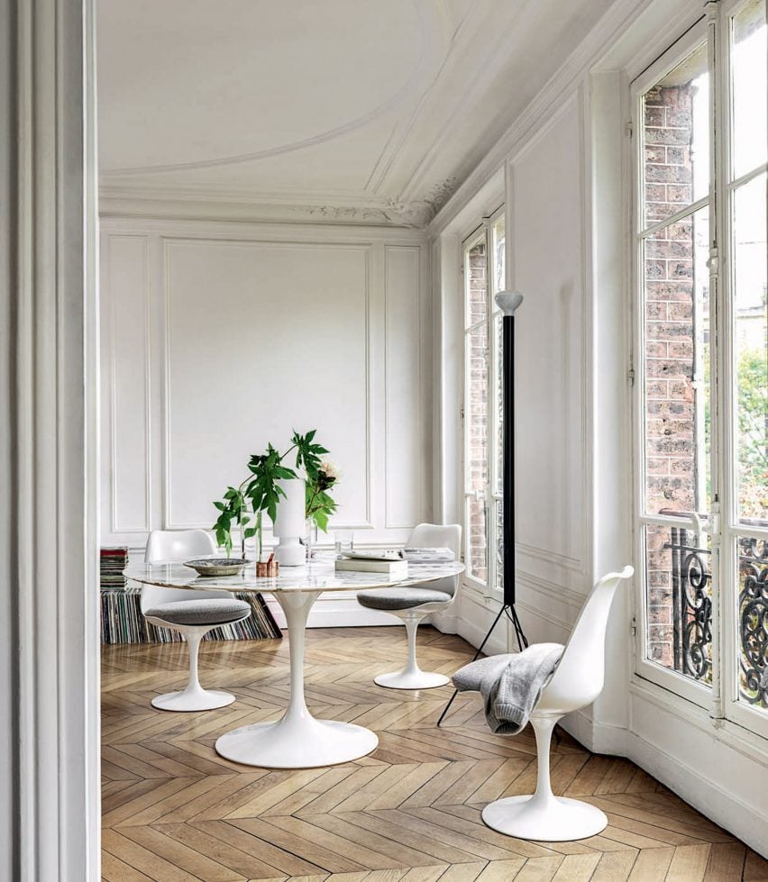 A modern white dining table set in white plastic with pedestal bases in a classic home interior