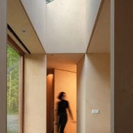 A wmoan walks through the hallway of Holiday Home by Orange Architects