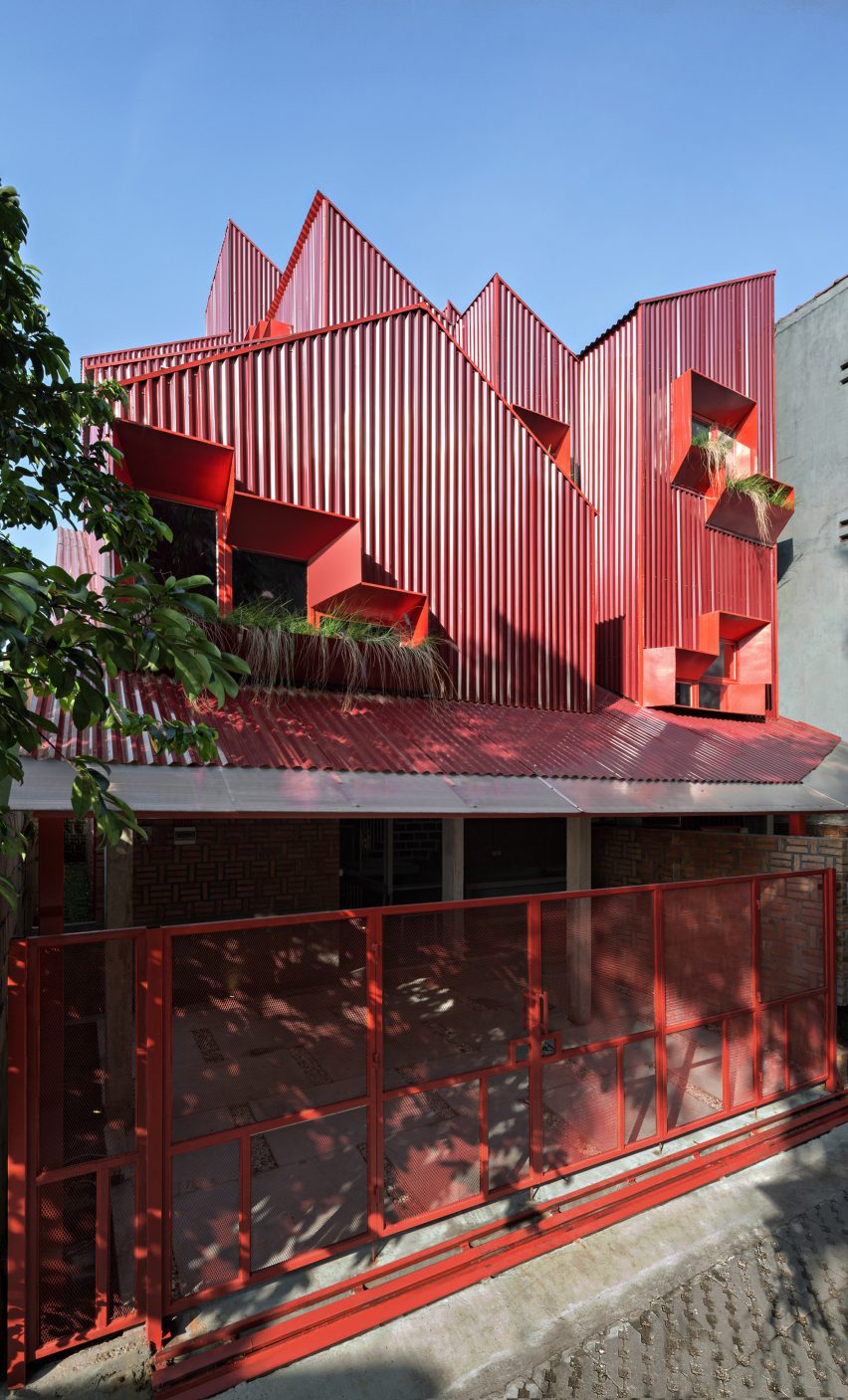 Exterior of red boarding house by Ismail Solehudin Architecture showing stacked volumes
