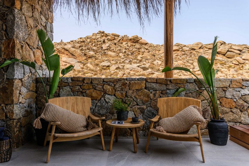 Wooden armchairs in front of stone wall of Mykonos Wellness Resort 