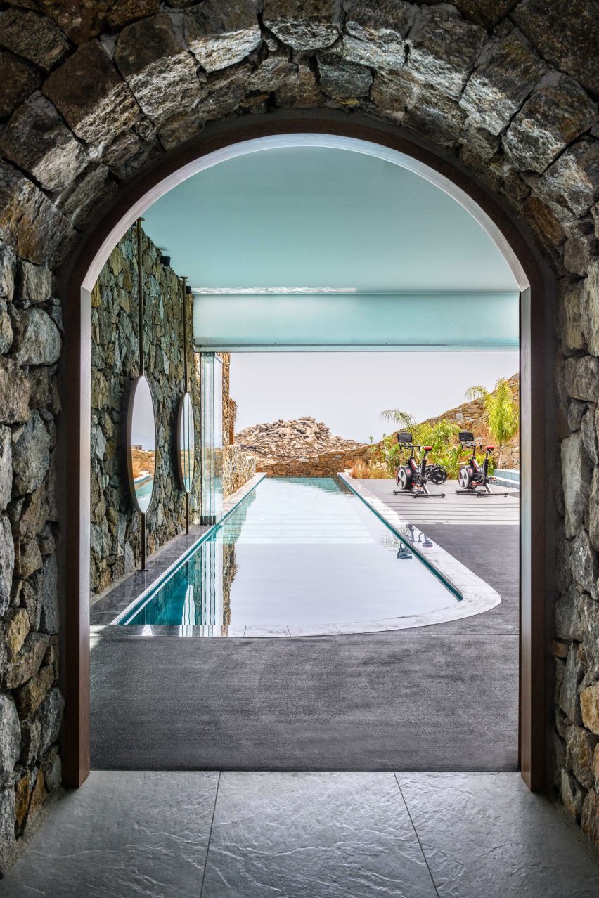 View through stone arch at Mykonos Wellness Resort at exercise bikes next to a pool