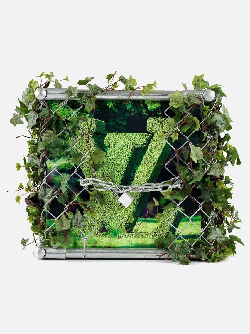 A green Louis Vuitton trunk covered in plants and a silver chain