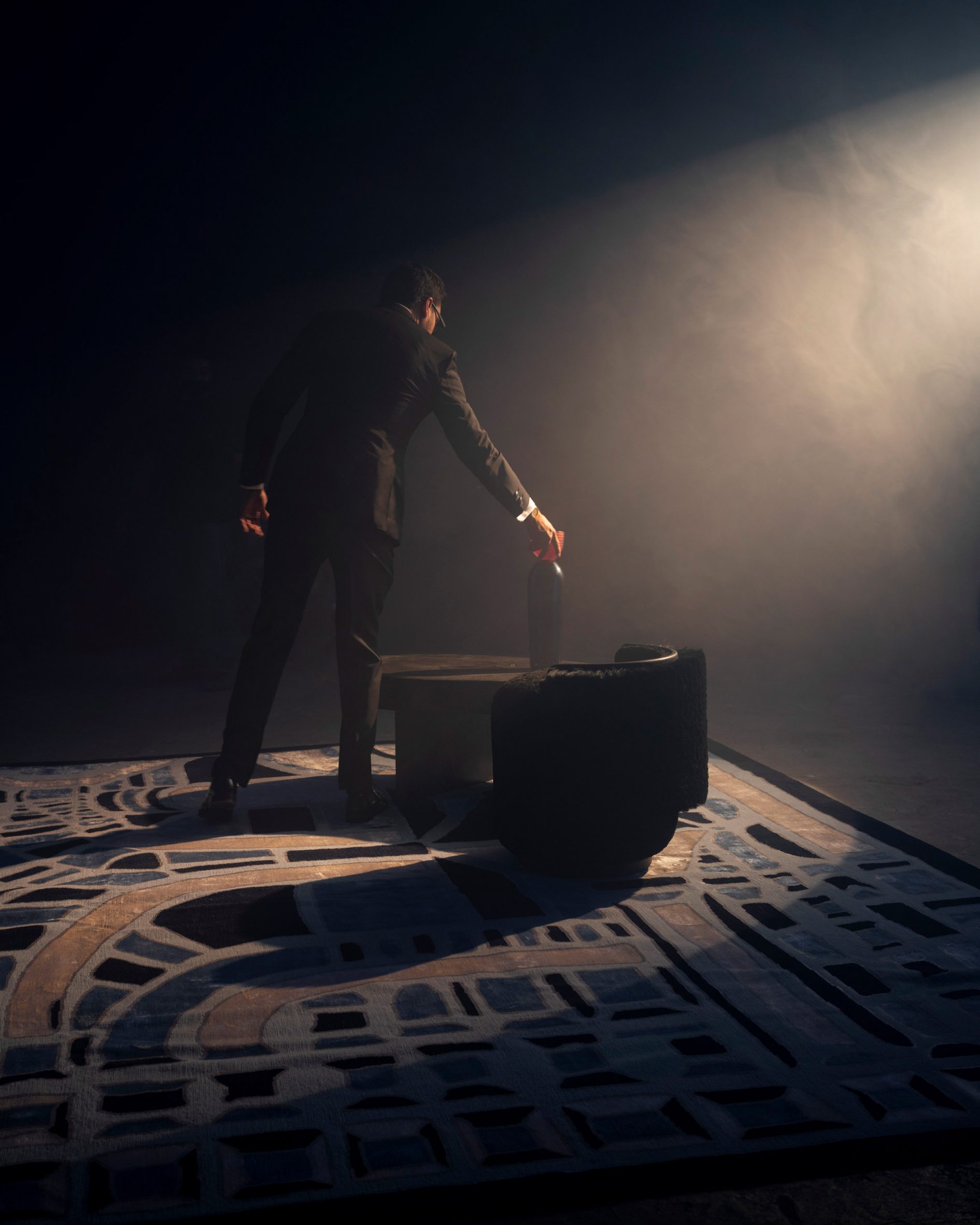 Man next to chairs on a blue and yellow mosaic rug by José María Balmaceda