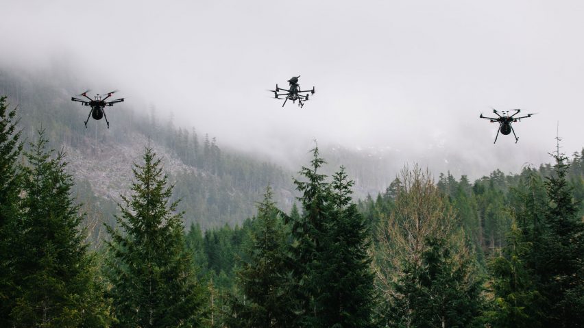 Three drones flying above a forest