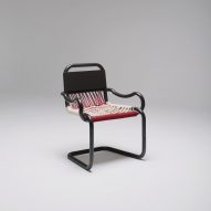 Black chair with red and white woven seat and curved armrests