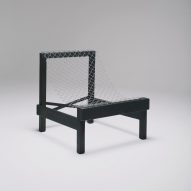 Wide black wooden lounge chair with metal wire seat
