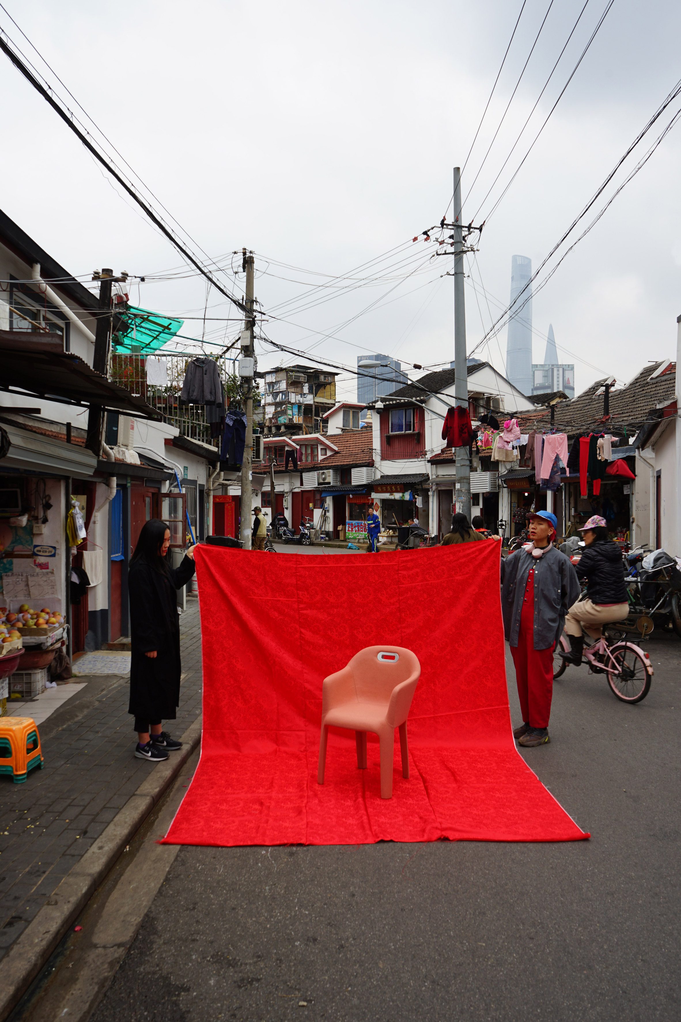 Chair photographed against a red sheet held by two locals on a Chinese street