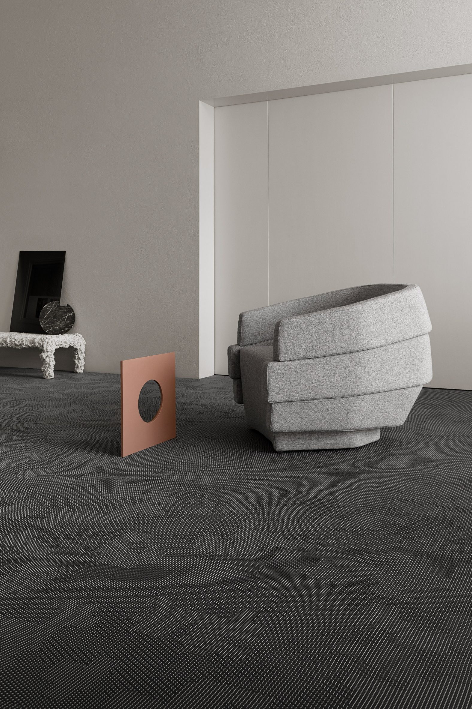 A grey armchair on Bolon by Patricia Urquiola flooring