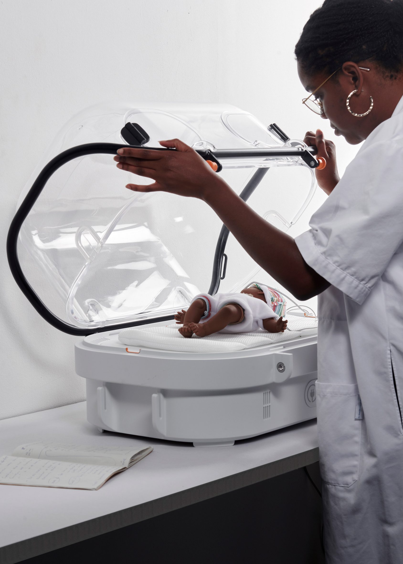 A woman checks a baby inside the white incubator