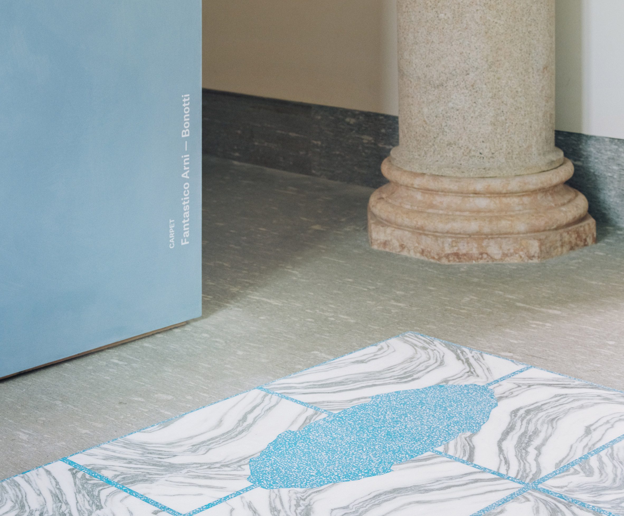 Tampilan dekat karpet Rumah Batu dengan pola pencocokan buku dengan batu biru dan putih