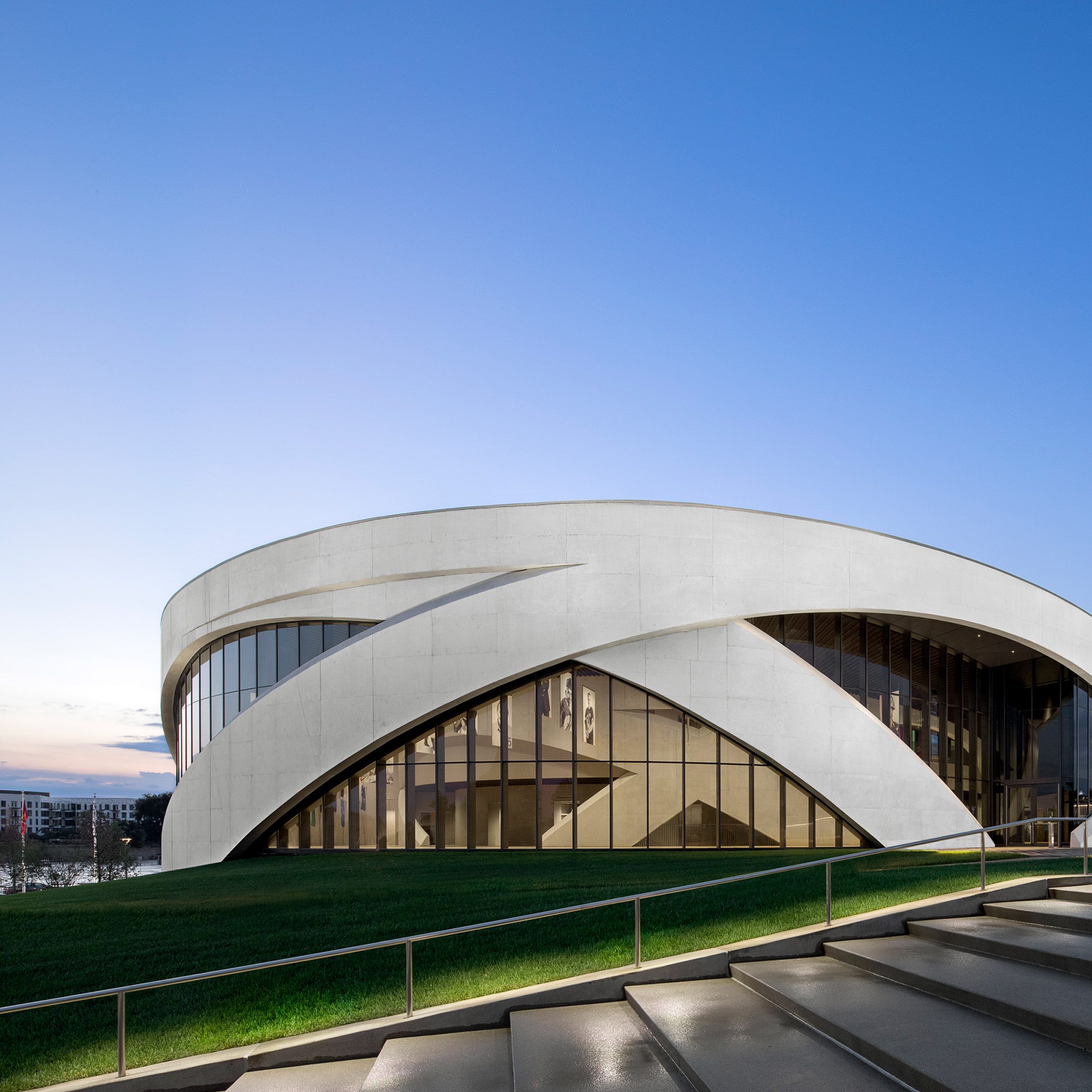 A large circular building with a glass facade and concrete arches enveloping the building