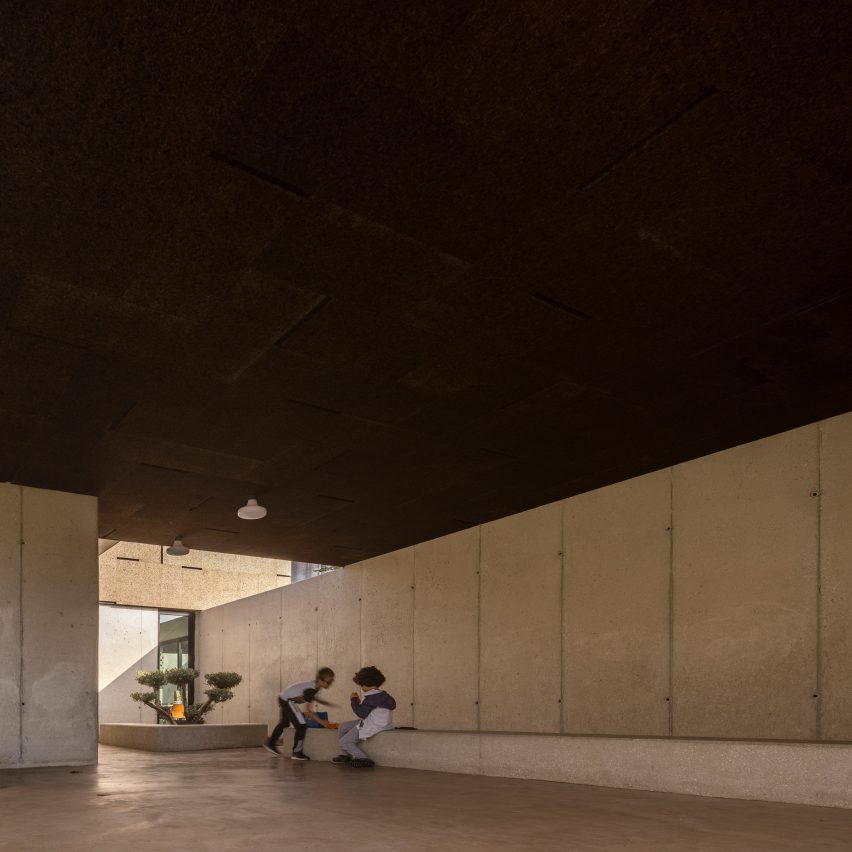 Covered courtyard of Casa da Arvore school with concrete panelled walls