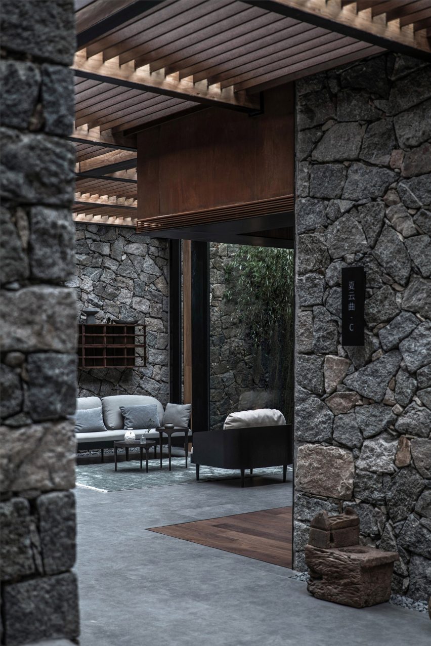 Seating nook surrounded by rough stone walls in hotel by Gad Line+ Studio