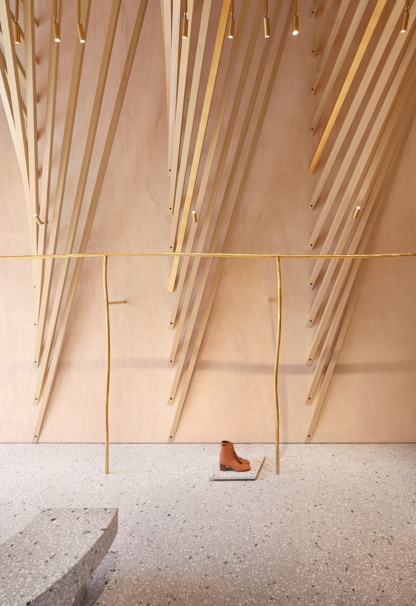 Gold-coloured clothes rails and terrazzo display plinth in Forte Forte shop interior