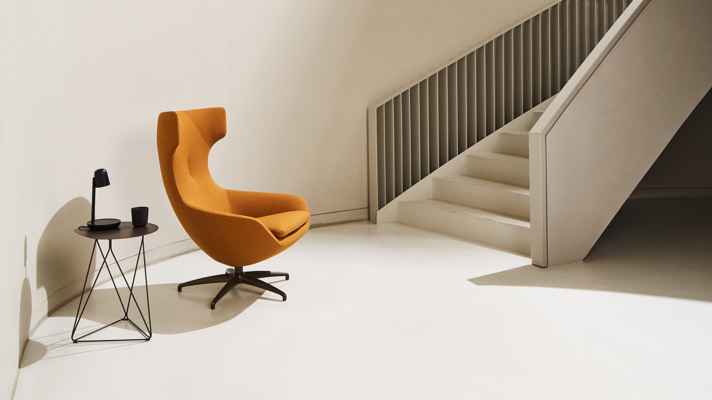 Bright orange LX662 armchair situated a neutral-coloured, pared-back room