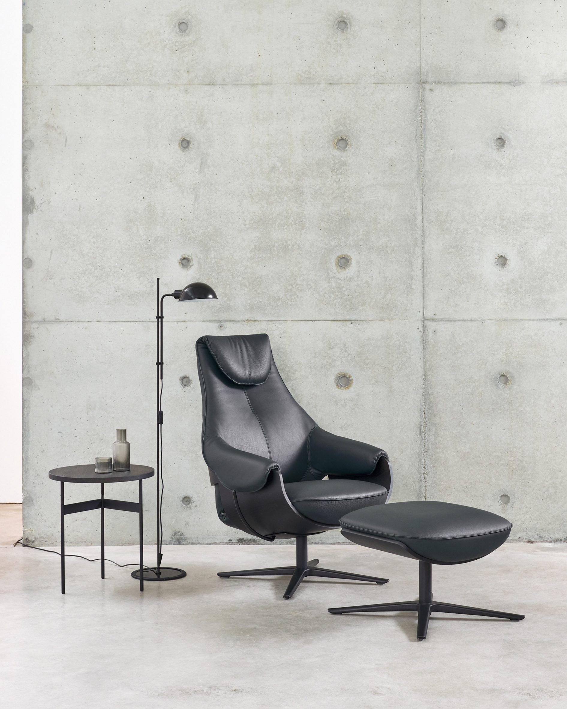 LXR10 armchair in a black leather finish with an accompanying footrest situated in a neutral-toned room