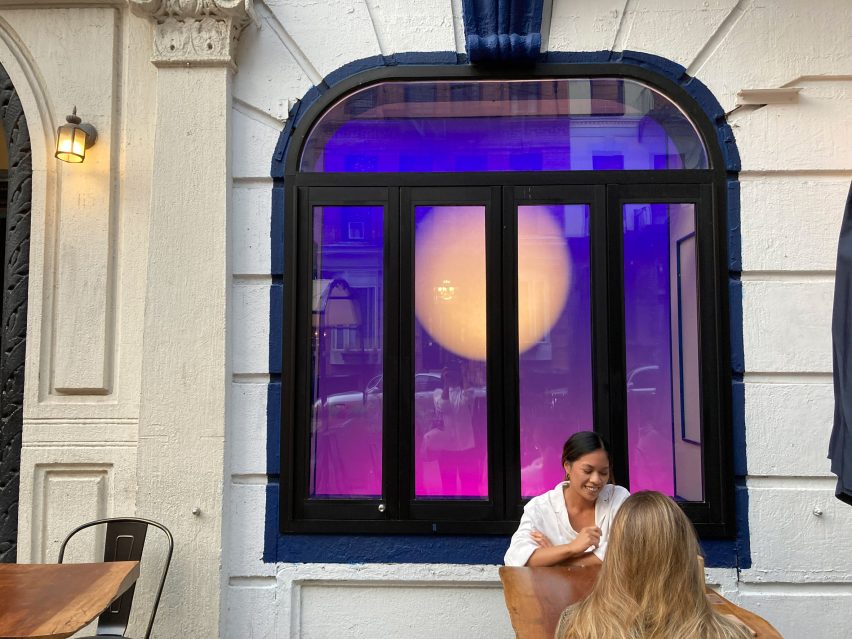 A woman sits in front of a window with purple lights