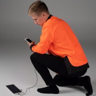 Man in orange jacket charges electronic devices