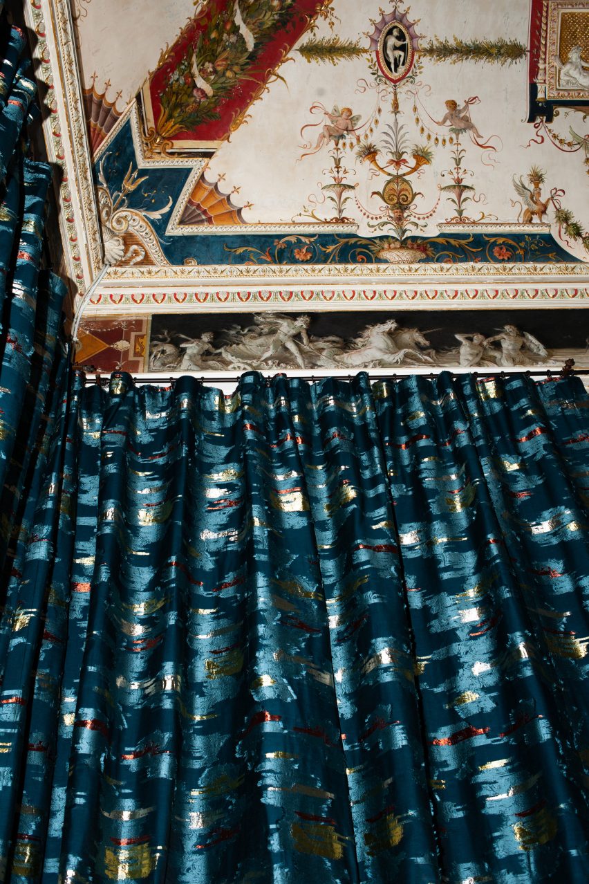 The Dalie Papaveri Tulipani fabric in blue with flecks of metallic gold and red being used as curtains