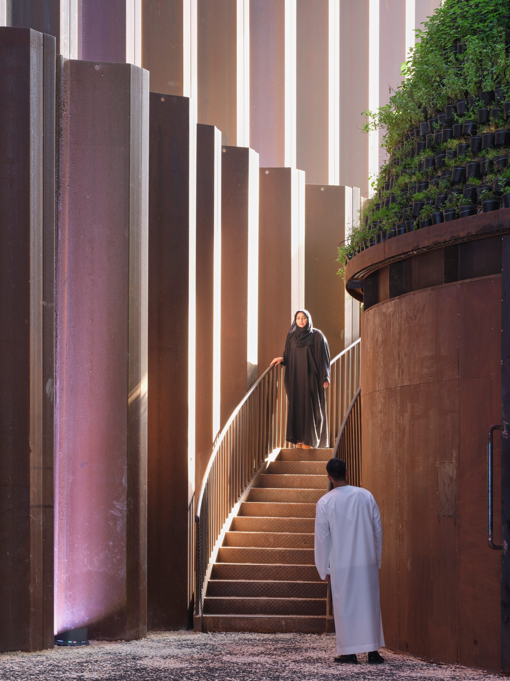 A woman walks down a circular staircase circling the green food cone at Dubai Expo 2020