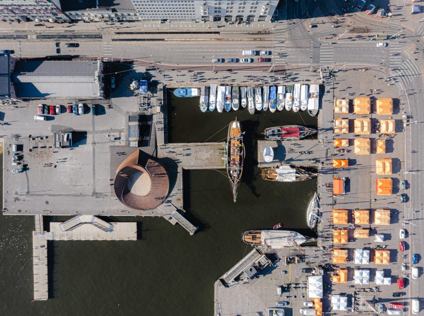 Aerial view of the circular Helsinki Biennial Pavilion among ships and buildings at the South Harbour