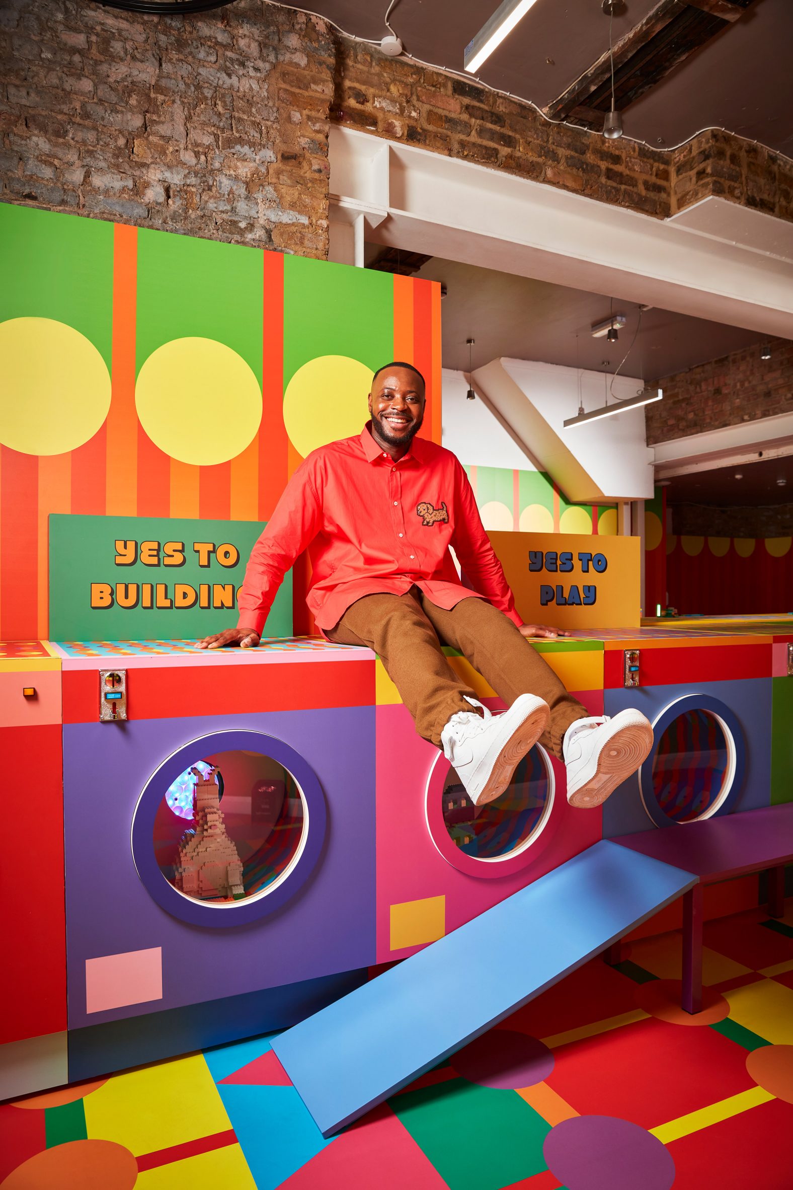 Yinka Ilori sits on a washing machine at the Laundrette of Dreams