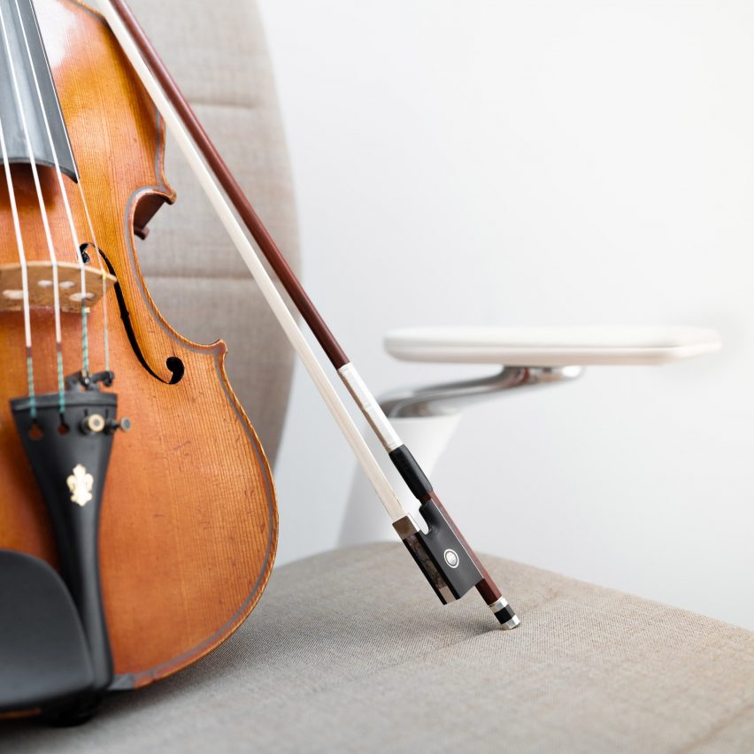 A photograph of a violin resting on a Kinnarps chair