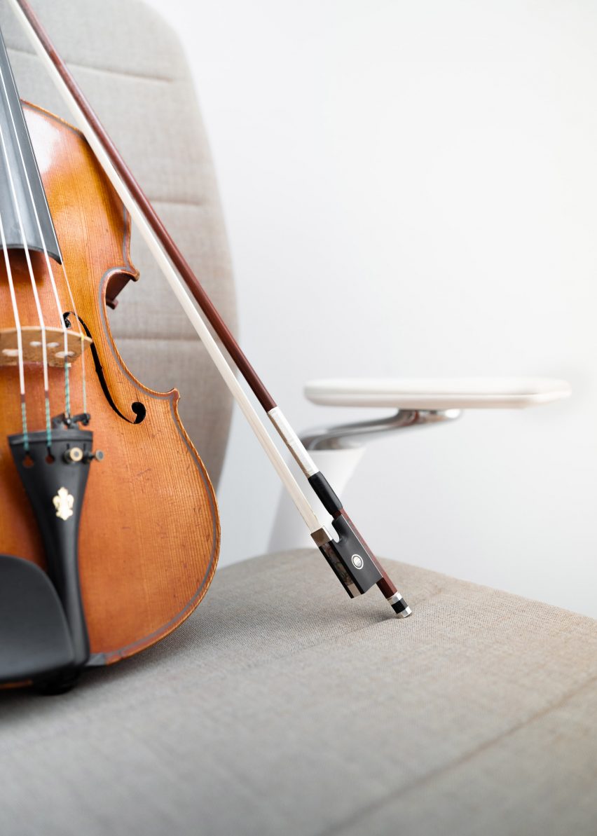 A photograph of a violin resting on a chair
