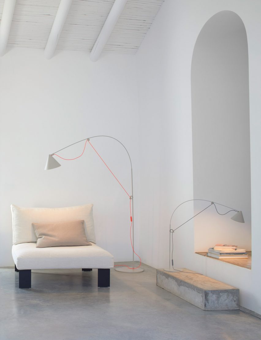Ayno light in Silk Grey with a bright orange cord perched over an armchair