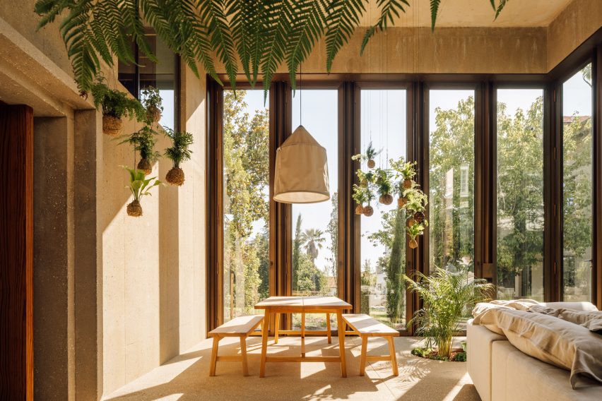 Ruang tamu paviliun taman oleh Bak Gordon Arquitectos dengan meja dan bangku perjamuan dan tanaman gantung