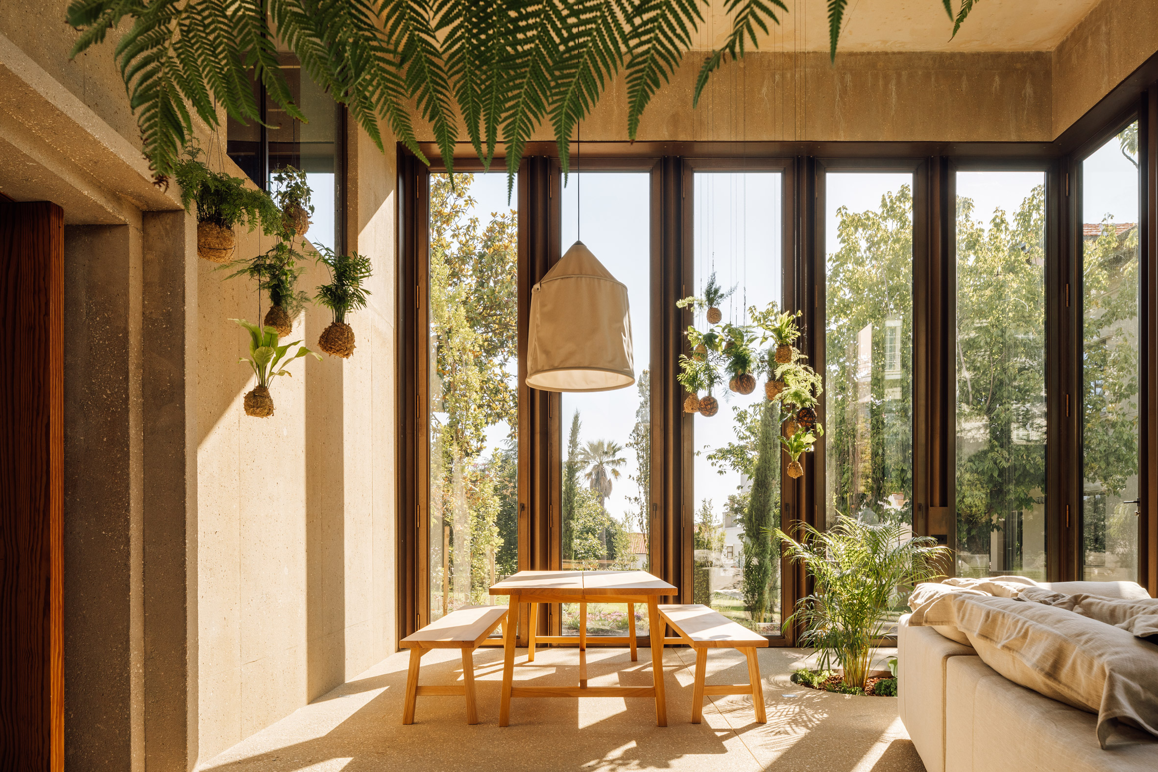 Living area of garden pavilion by Bak Gordon Arquitectos with banquet table and benches and hanging plants